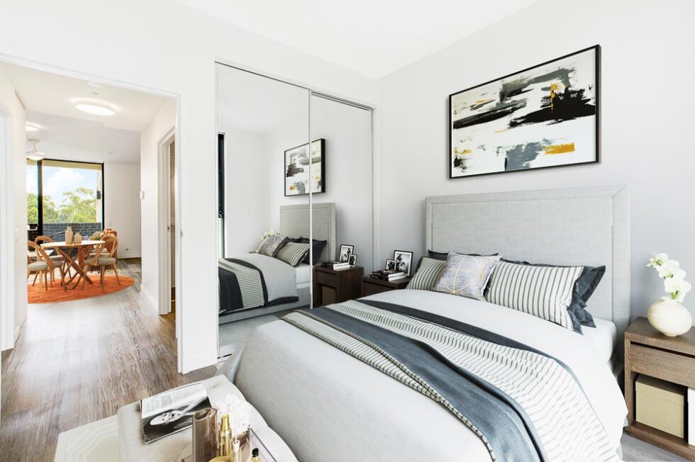 Main bedroom of display furnished unit looking through to dining area and balcony
