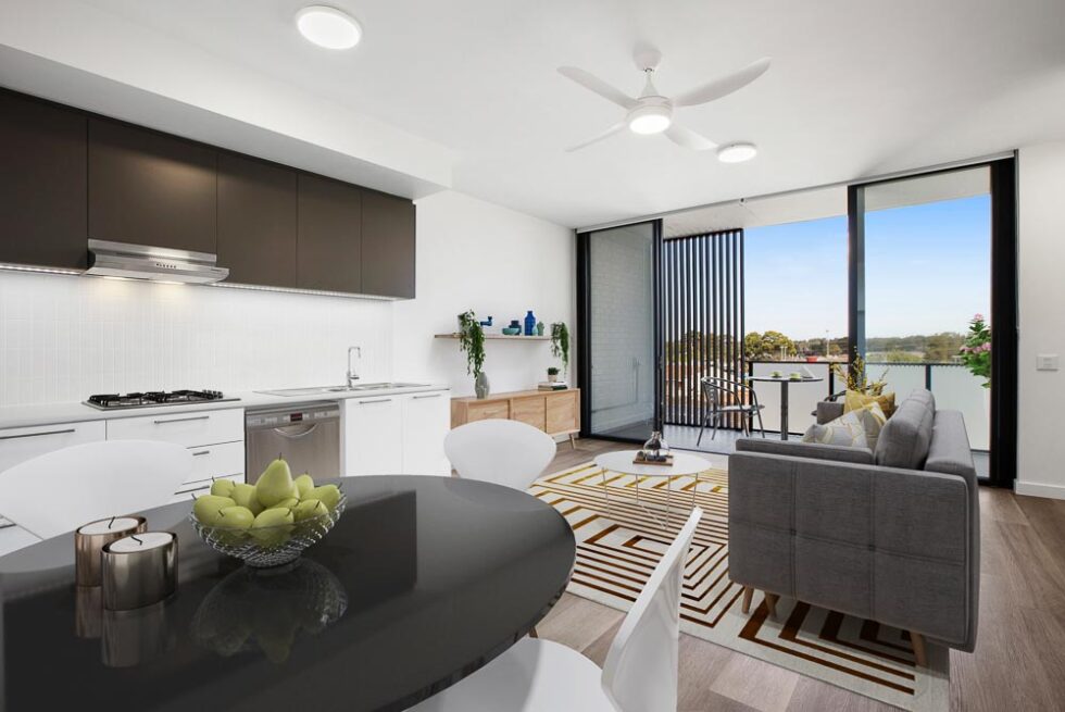 Kitchen and dining area of display furnished unit looking through lounge area and out to balcony