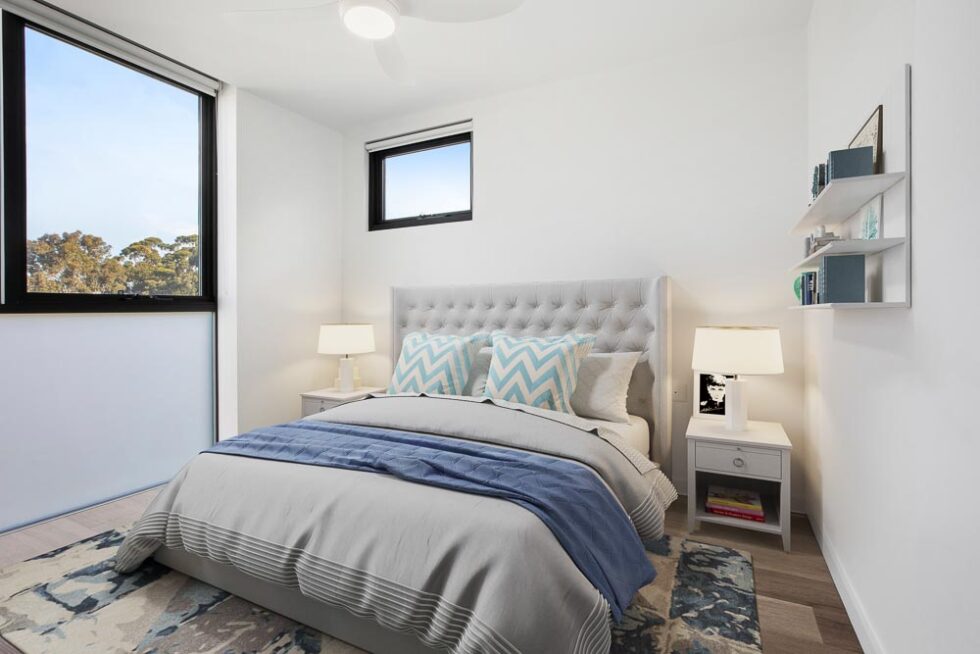 Main bedroom of display furnished unit, with double bed, bedside table, full width windows