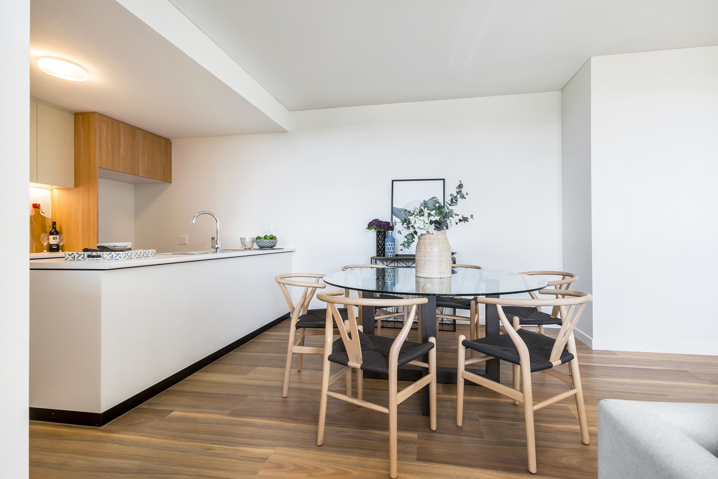 Indoor dining table and kitchen area of bright, clean unit