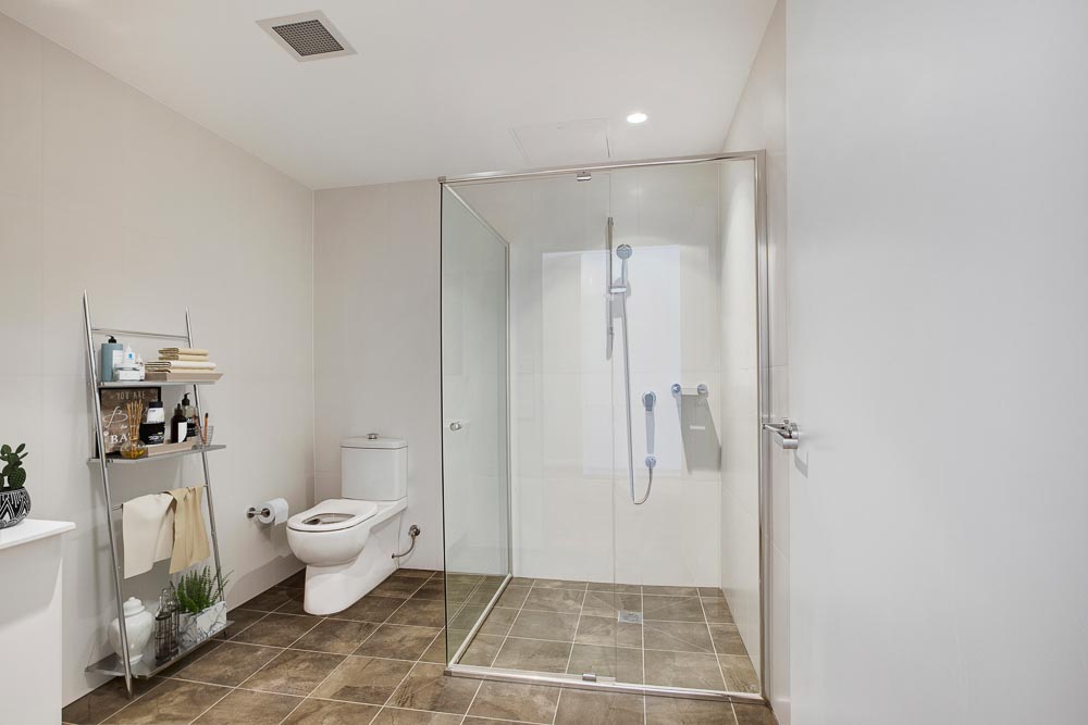 Bathroom of new unit, display furnished with a spacious shower