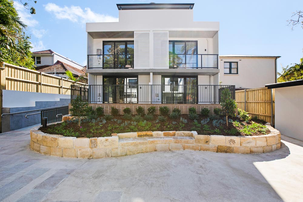 Two storey building seen from back yard with a raised garden bed