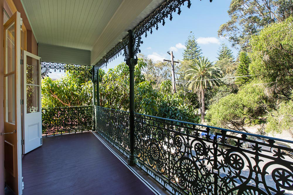 View from balcony with wrought iron railings over tree filled street