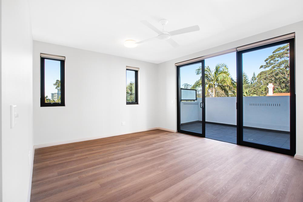 View of unfurnished bedroom and balcony looking over leafy suburb