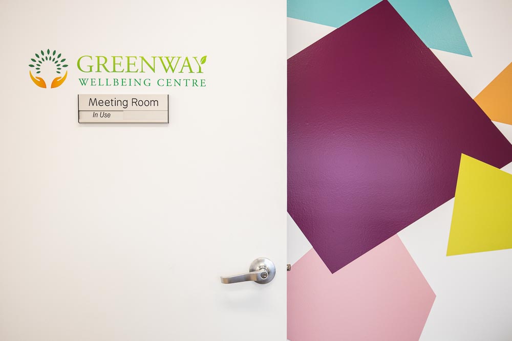 A door with signage that says Greenway Wellbeing Centre and a status slider "meeting room: In use"