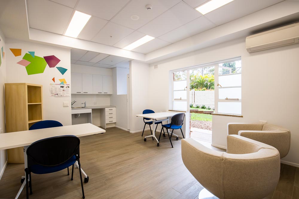 A spacious community room with comfortable chairs, kitchenette and one-to-one meeting desks