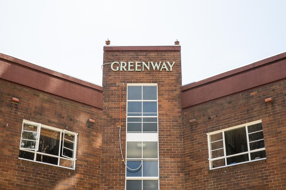 A sign on the side of a large building that says Greenway