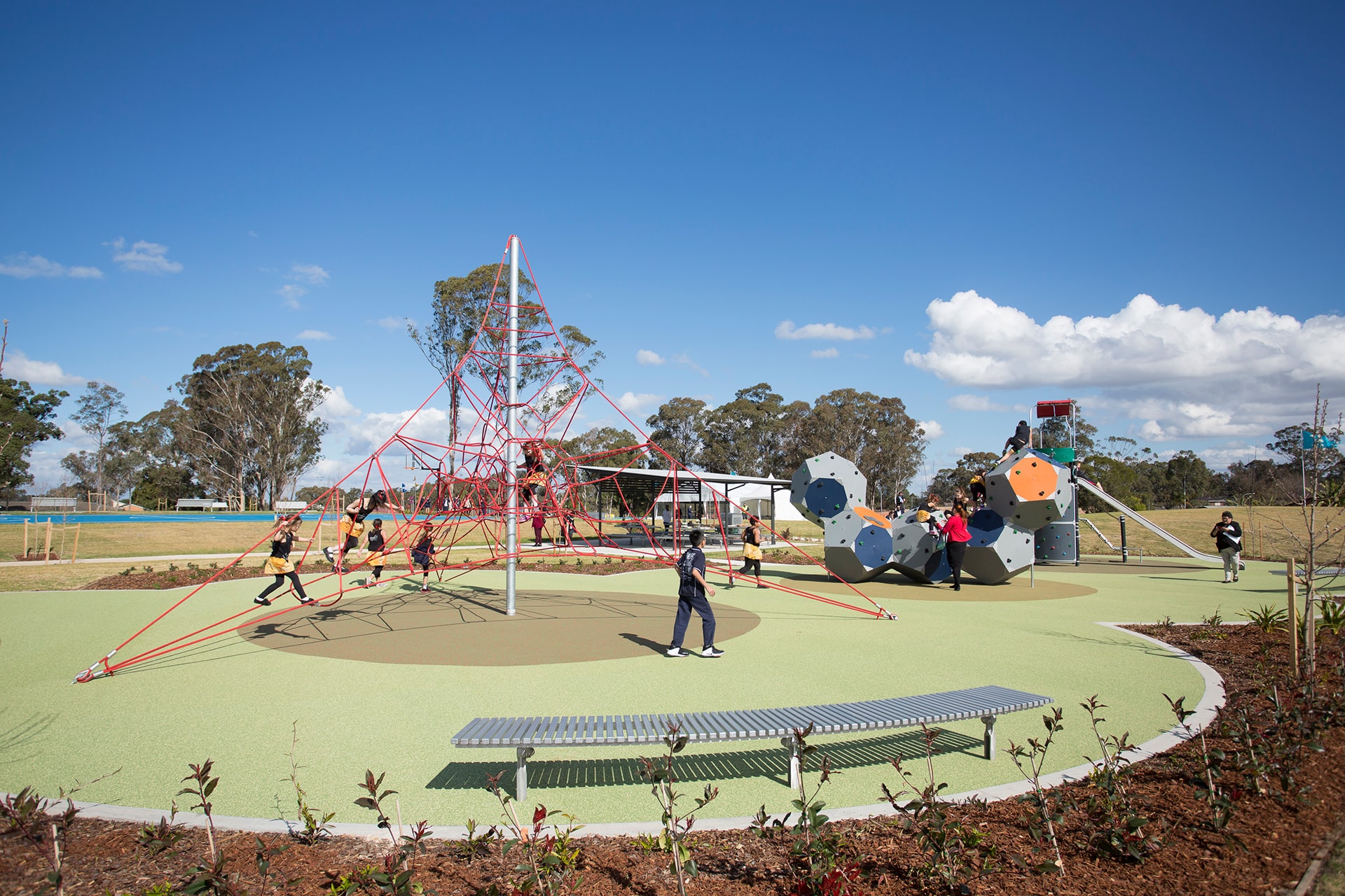 Teenagers playing on an unusual and creative playground with climbing webs and structures and a slide