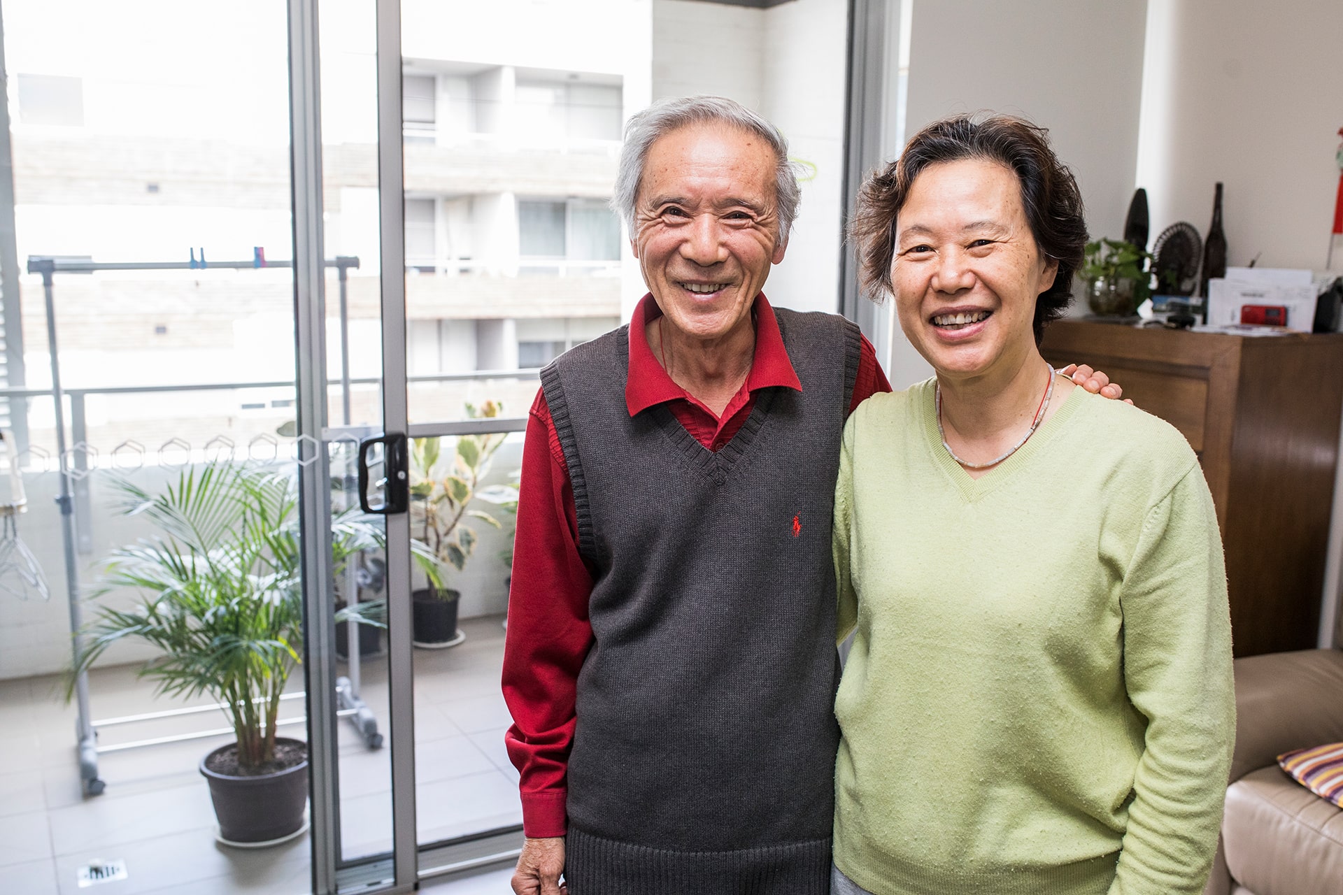 Smiling senior couple standing in front of the view from their balcony