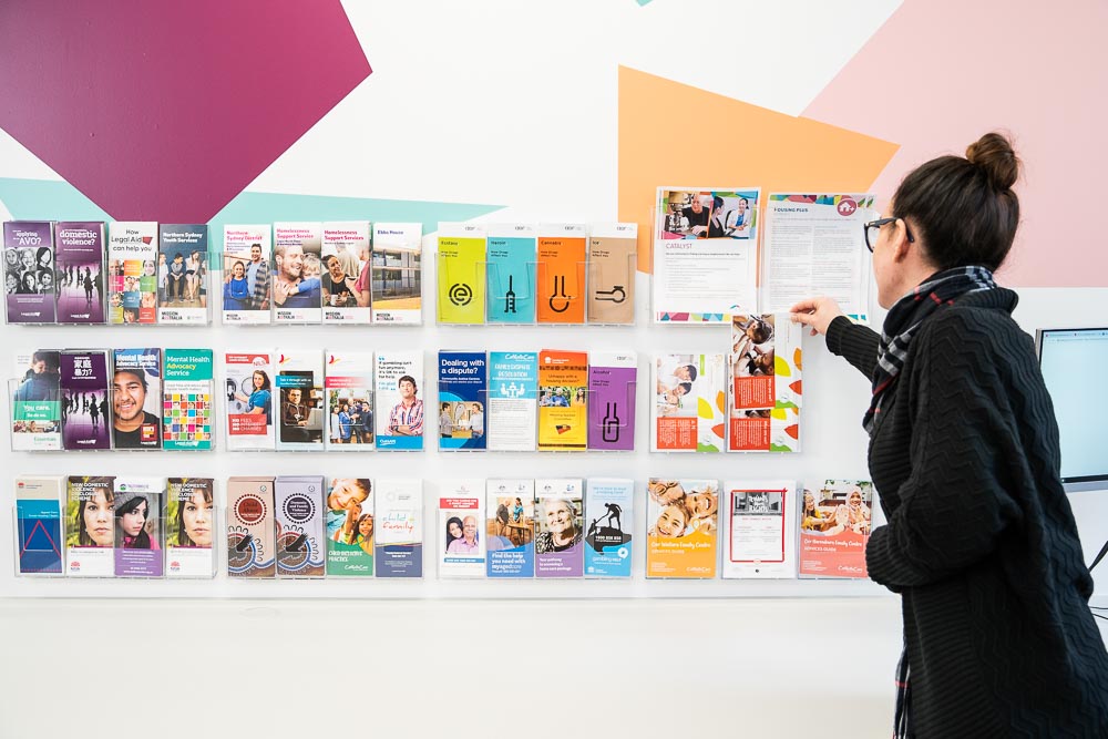A woman looking at a wall display of brochures