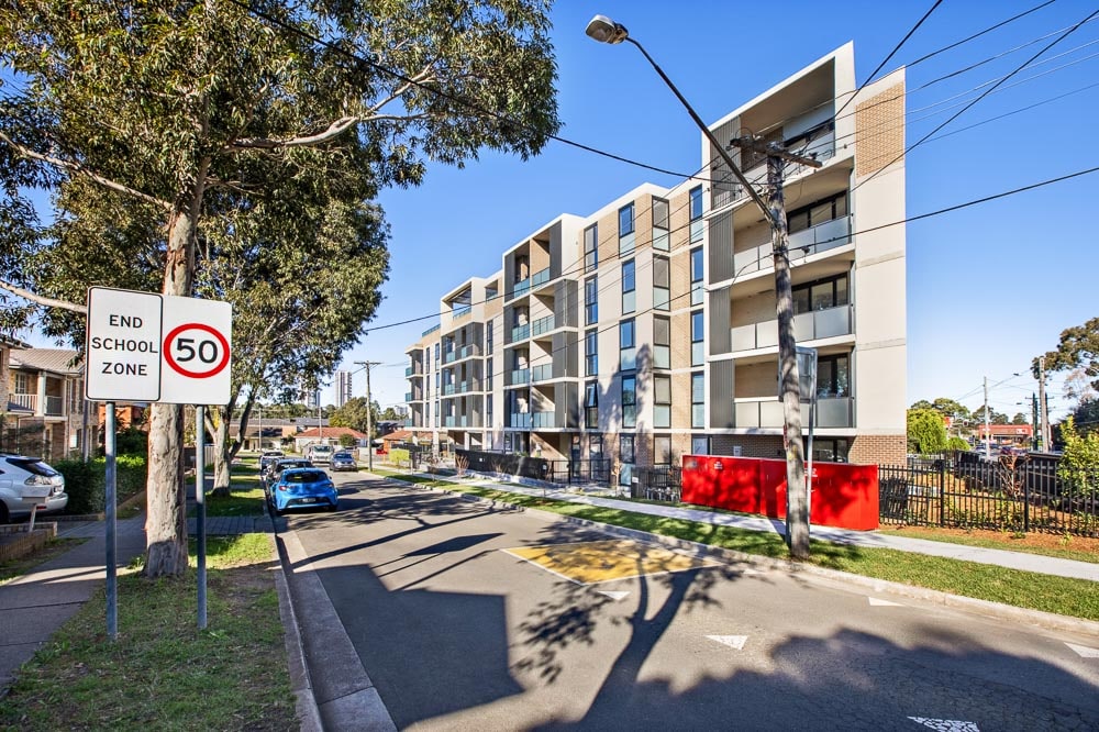 5 story building on a suburban street with trees and school zone sign