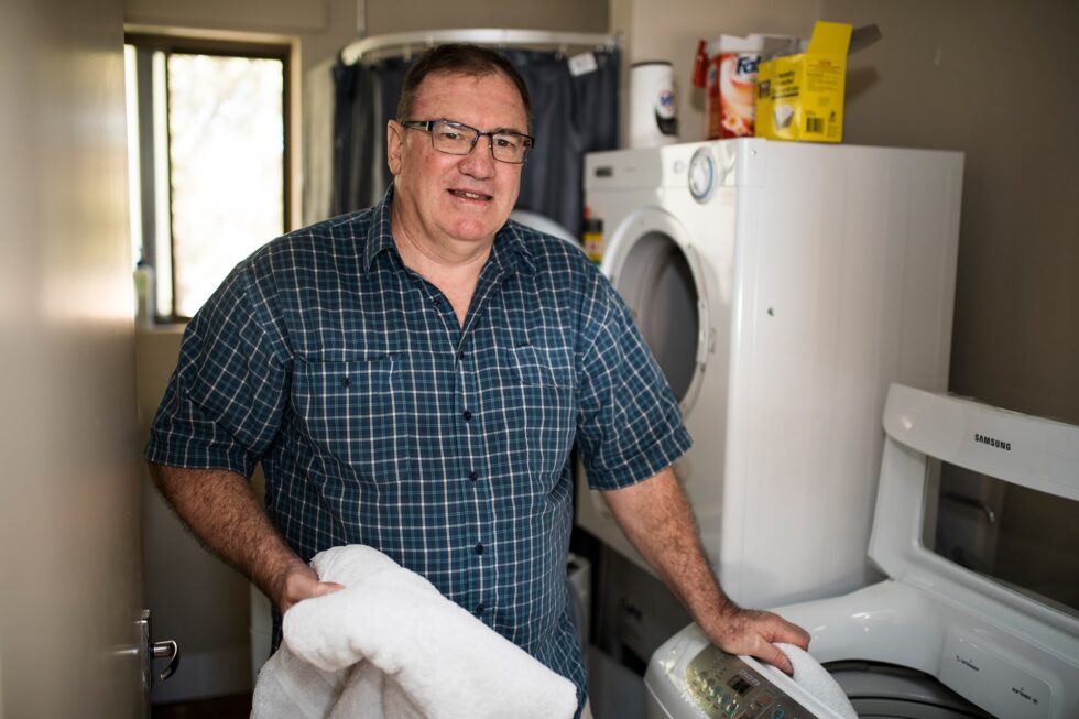 A customer in his laundry at home using washing machine