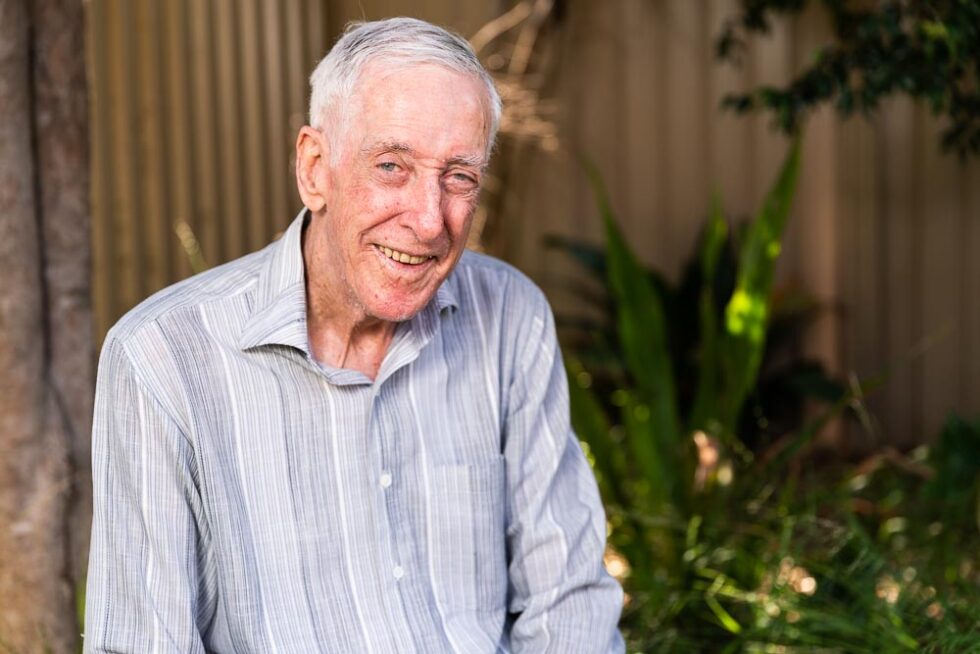 A senior customer smiling in his garden