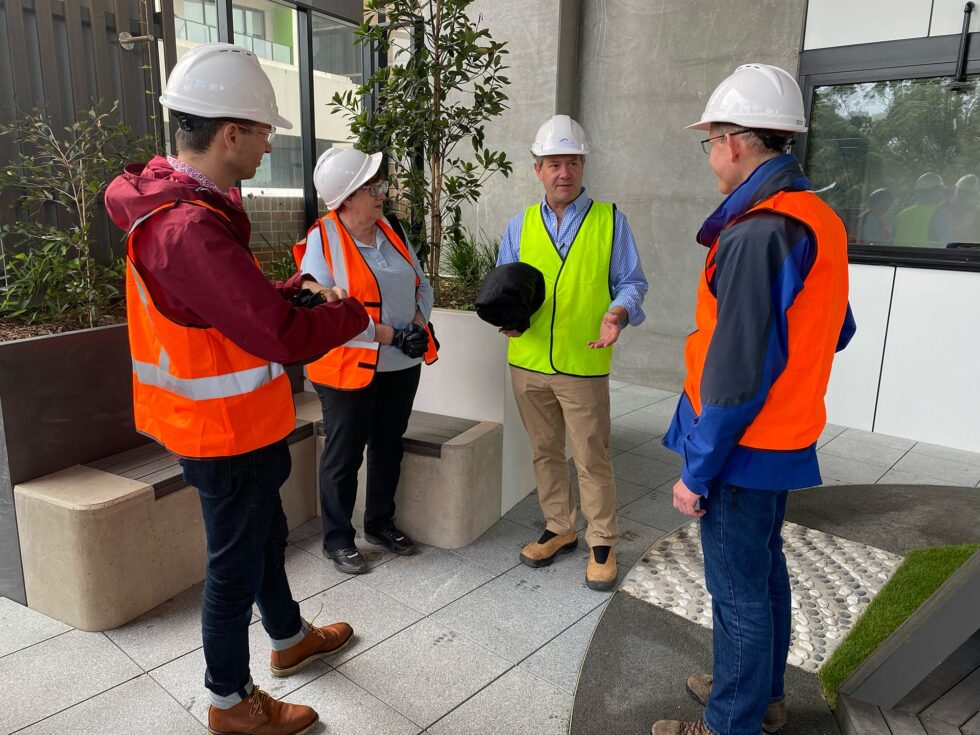Andrew Brooks giving a tour of a work site to visitors in hi vis and hard hats