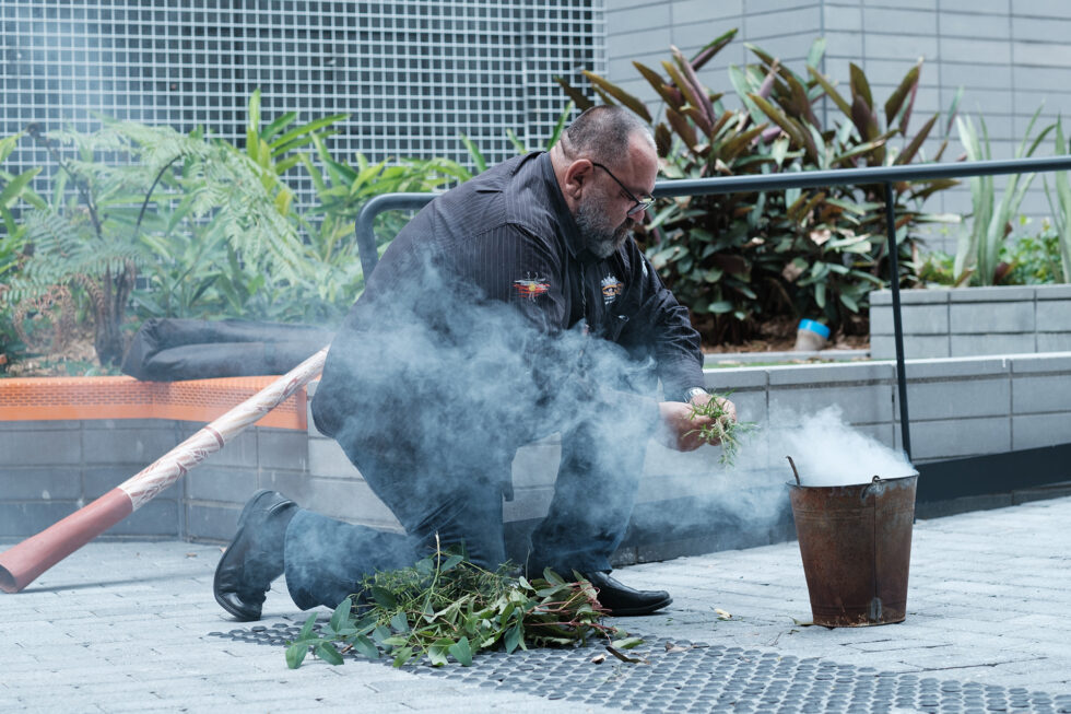 A man kneeling to perform a smoking ceremony