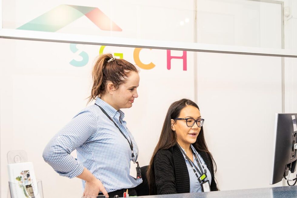 Staff members in front of SGCH sign looking at something on computer