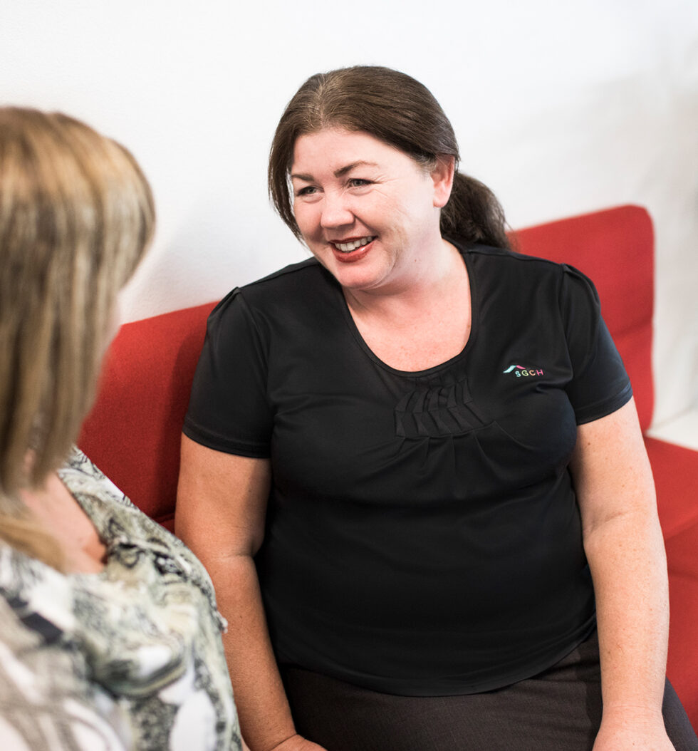 Two women speaking to each other on a bench seat in SGCH reception