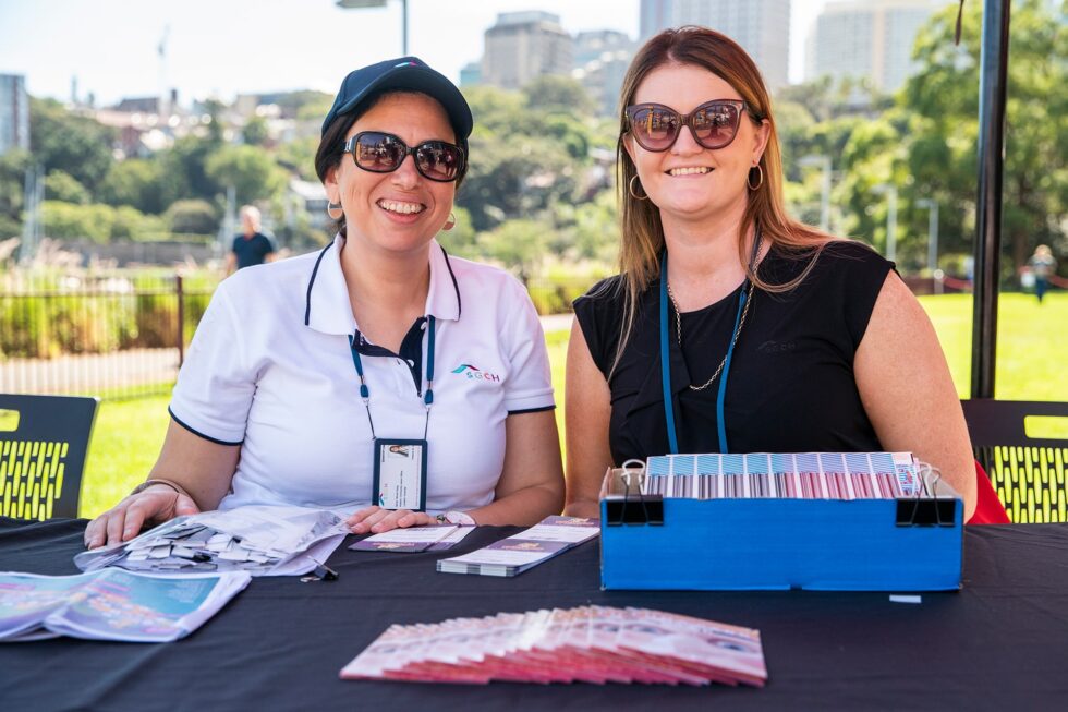 Two smiling staff in sunglasses working at the registration desk