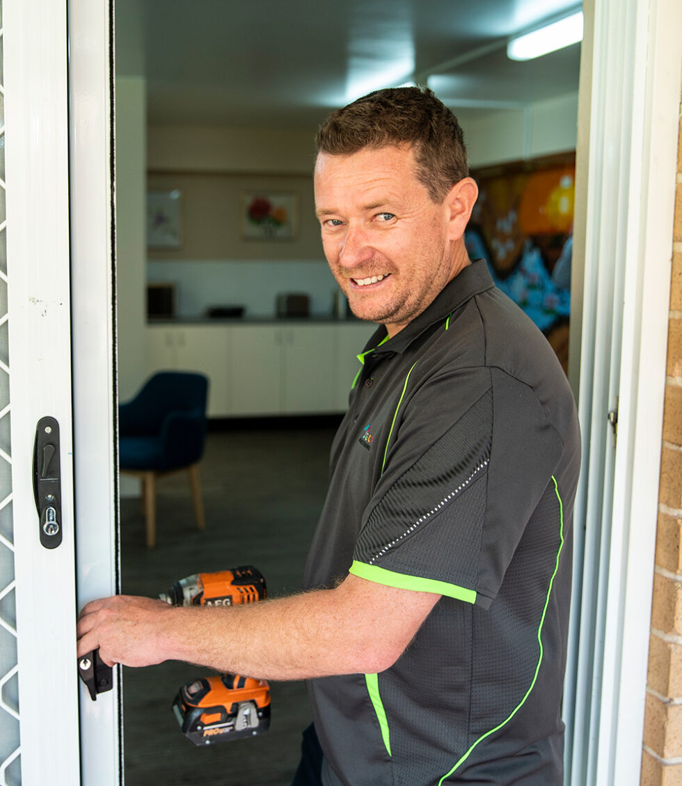 SGCH handy person with a drill working on a doorway