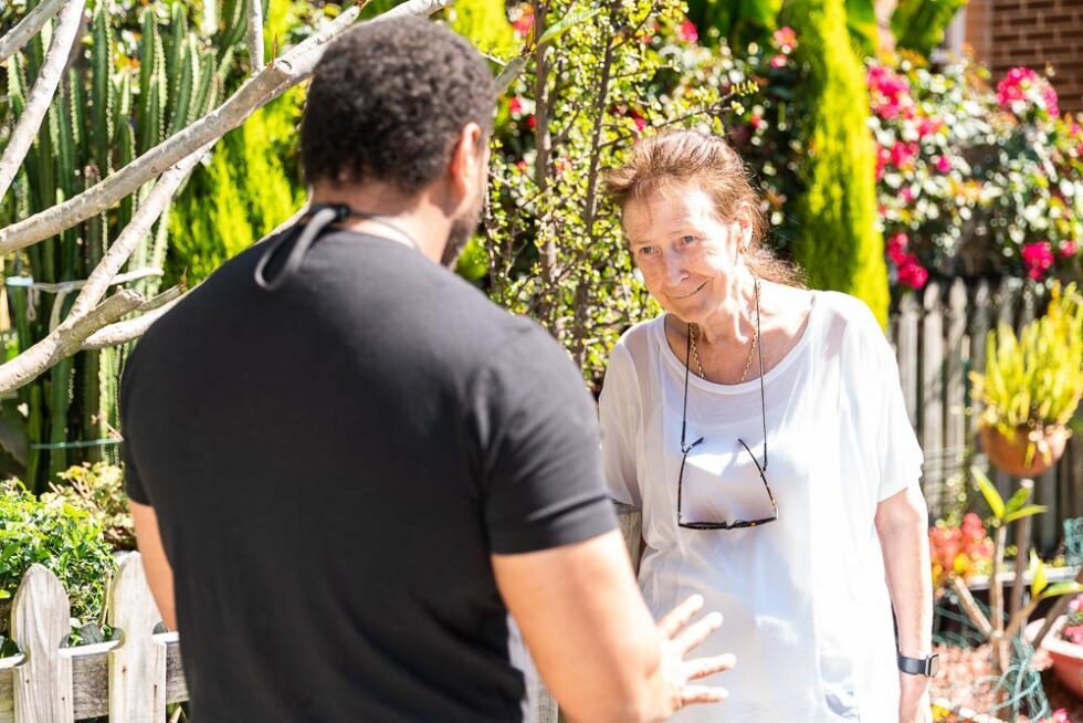 A tenancy manager speaking to a senior woman in a beautiful garden