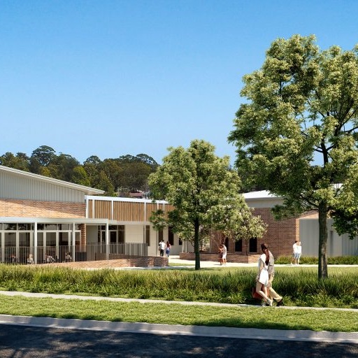 Two people walk along a footpath outside a community building near trees