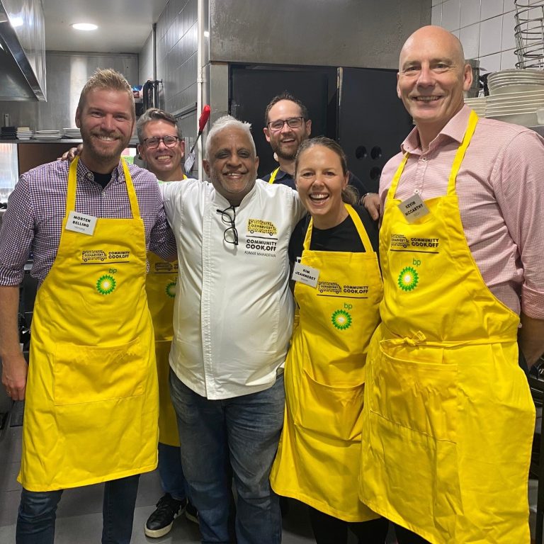 Six smiling people in a restaurant kitchen