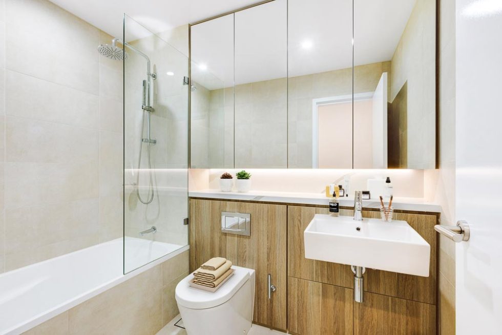 Bathroom of a furnished unit with a bathtub shower and large mirrors