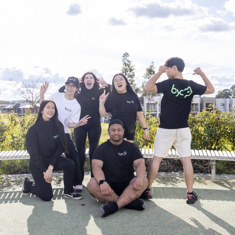Six teenagers posing for a fun group photo in the park