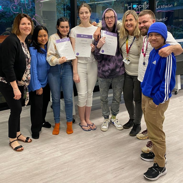 A smiling group of 8 people including 3 young adults holding up certificates