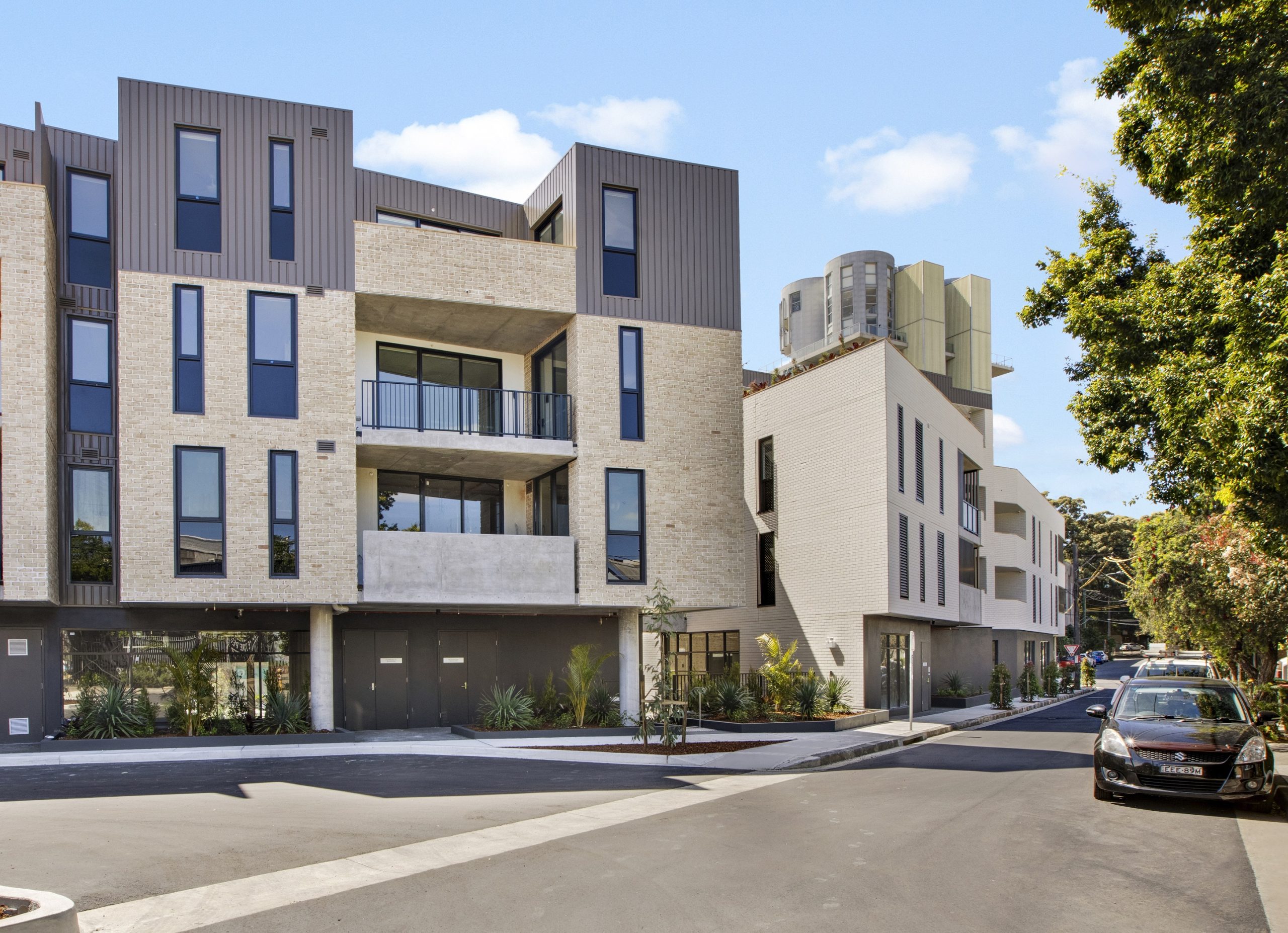 Four story building on the corner of a leafy street