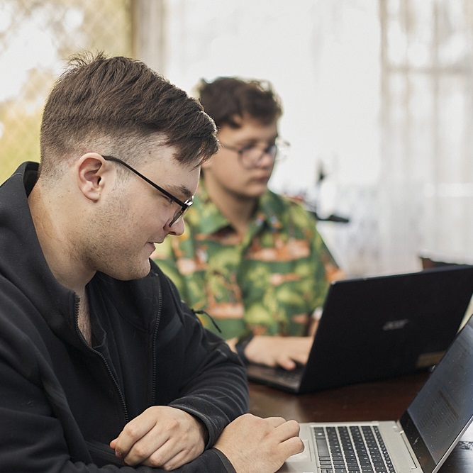 Two young men in casual clothes using laptops at home