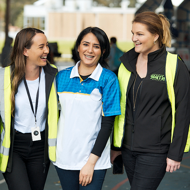 Three women laughing together in casual work clothes