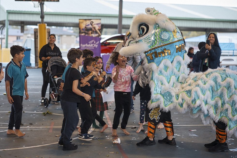 A group of excited children surround the 'lion' during a Chinese Lion Dance