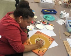 Maureen painting at a table during art class