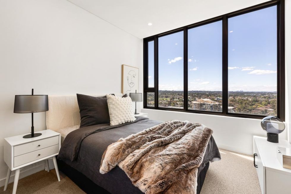 Bedroom of a dressed display unit with a view out over Parramatta