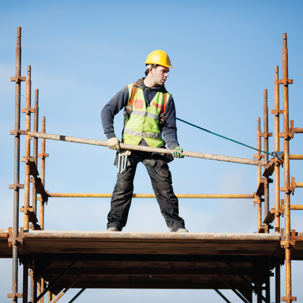 A worker on scaffolding wearing hi visibility vest and hardhat