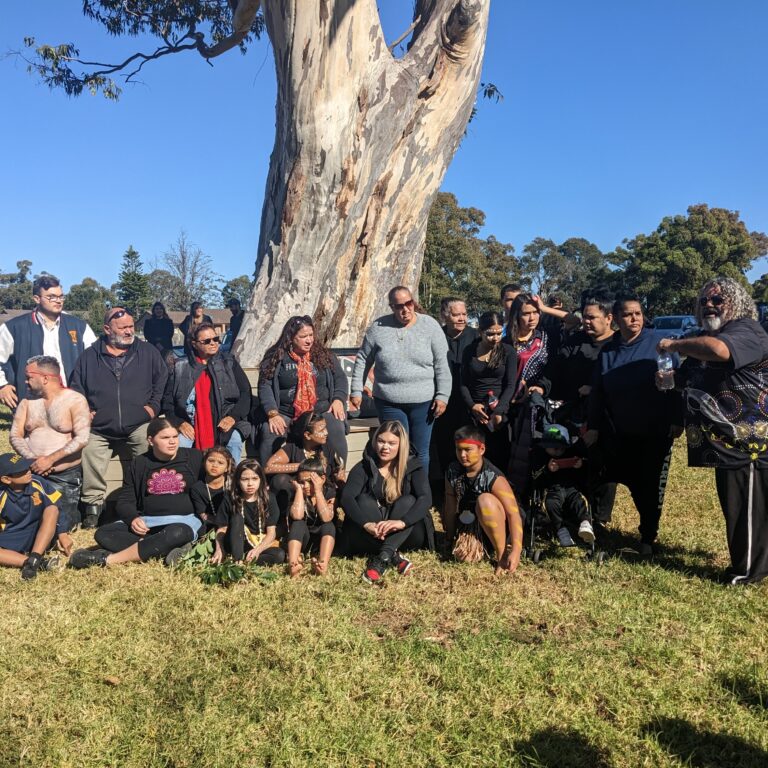 21 members of Aunty Yvonne's family, from toddlers to adults, gathered for a photo in front of her tree