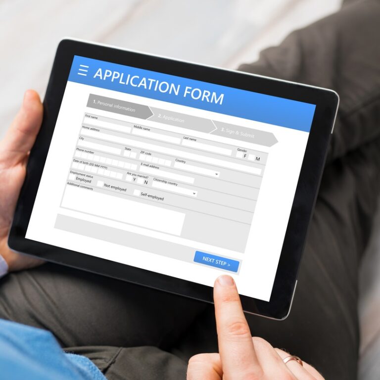 Close up of a man using a tablet device to fill in a digital application form
