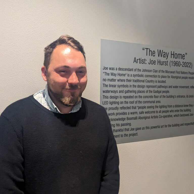 Djardie Hurst standing in front of the plaque honouring his father Joe and Joe's art